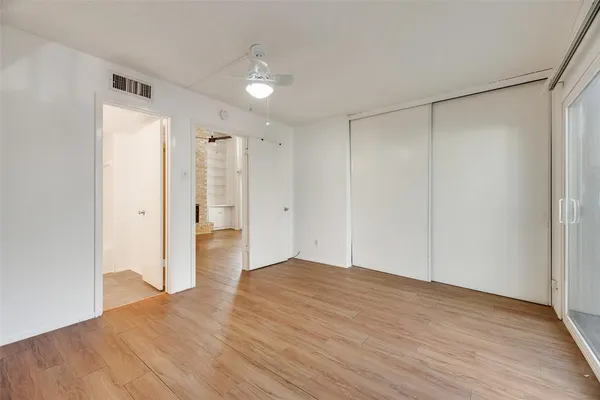 a view of an empty room with wooden floor and a bathroom