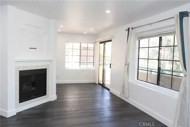 an empty room with wooden floor fireplace and windows