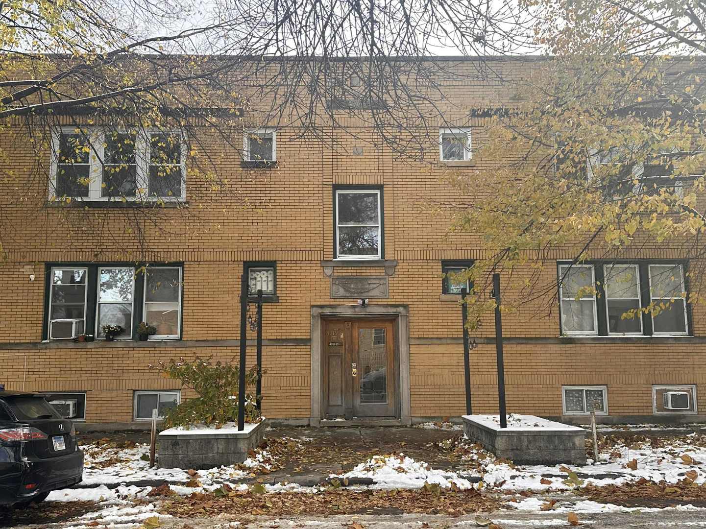 a front view of a building with large trees