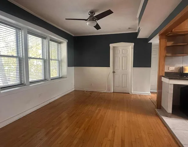 a view of an empty room with a window and wooden floor