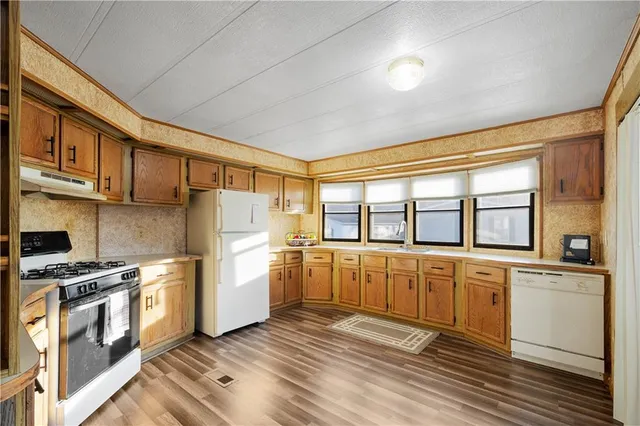 a kitchen with stainless steel appliances granite countertop a refrigerator a stove and a sink with cabinets