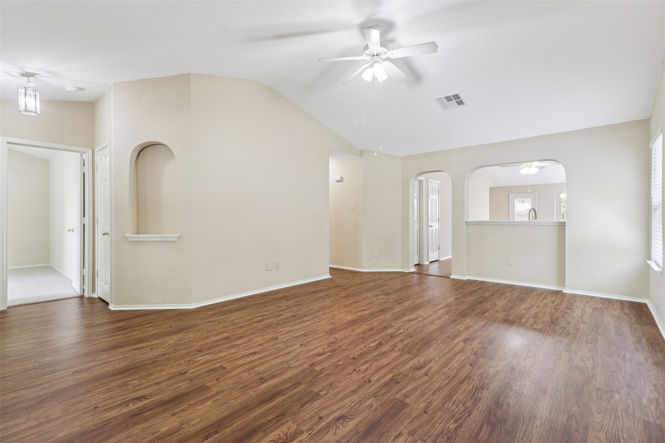 700 Scheel Road Kyle, TX 78640 - Photo 6 of 39 Spacious living area featuring vaulted ceilings, ceiling fans, wood-look flooring, and an arched wall niche