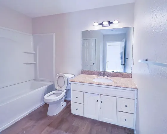 a spacious bathroom with a granite countertop toilet a sink and a bathtub