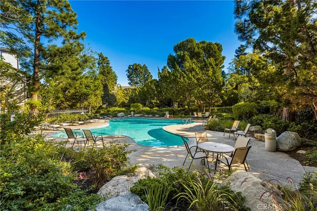 a view of a swimming pool with outdoor seating and trees
