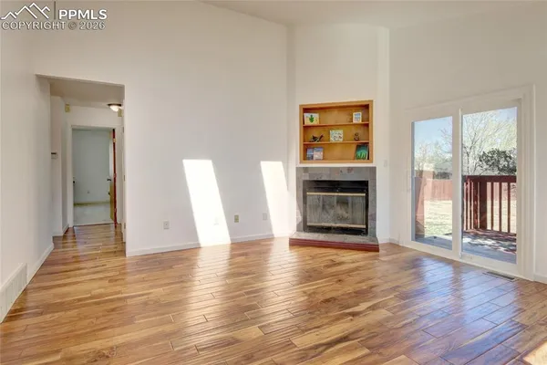 a view of an empty room with window and fire place