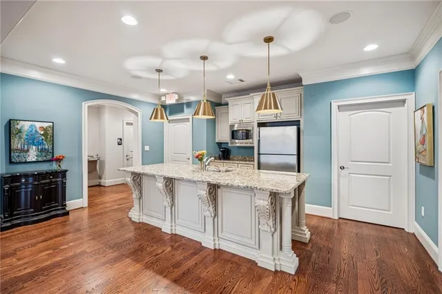 an open kitchen with wooden floor and refrigerator