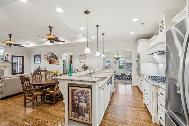 a kitchen with stainless steel appliances kitchen island granite countertop a table chairs and a wooden floor