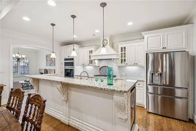 a kitchen with kitchen island a refrigerator a stove a sink and wooden floor