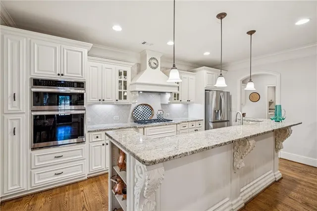 a kitchen with kitchen island granite countertop a stove a oven a counter space and wooden floor