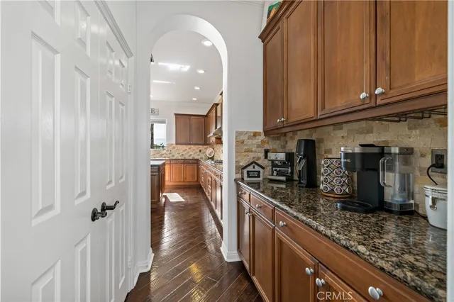 a kitchen with stainless steel appliances granite countertop a stove top oven a sink a dining table and chairs with wooden floor