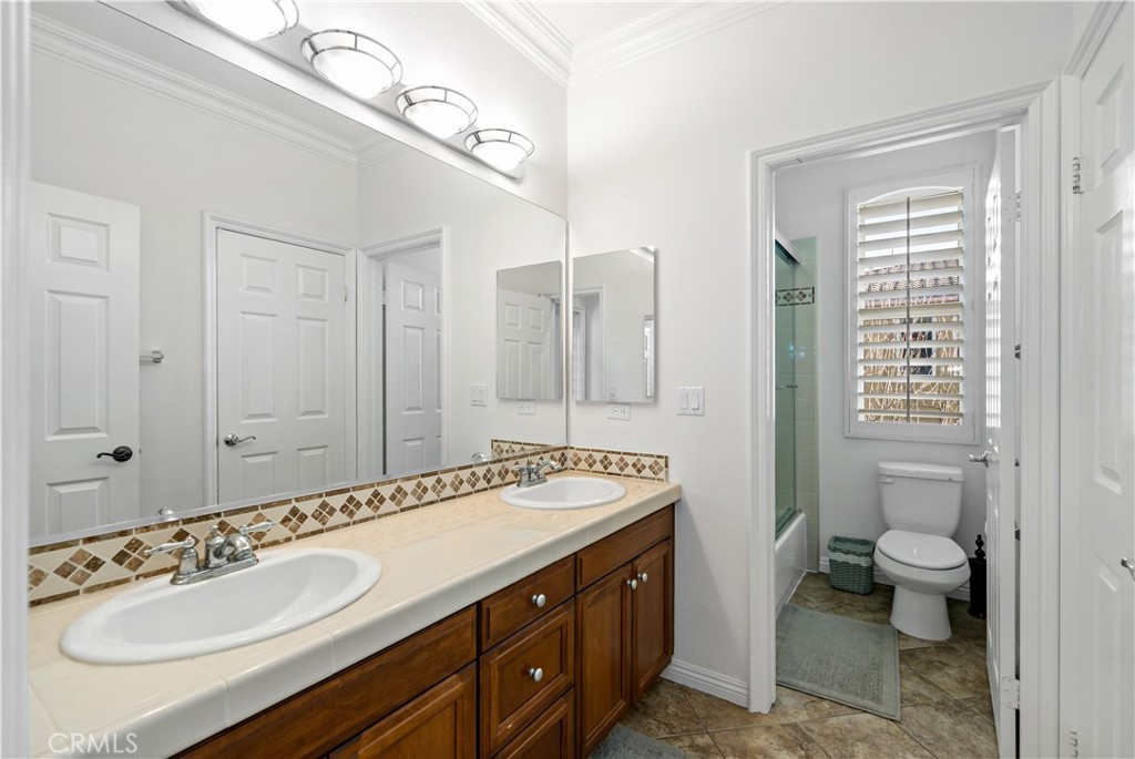 16423 Village Meadow Drive Riverside, CA 92503 - Photo 34 of 63 a spacious bathroom with a granite countertop double vanity sink a mirror and a toilet