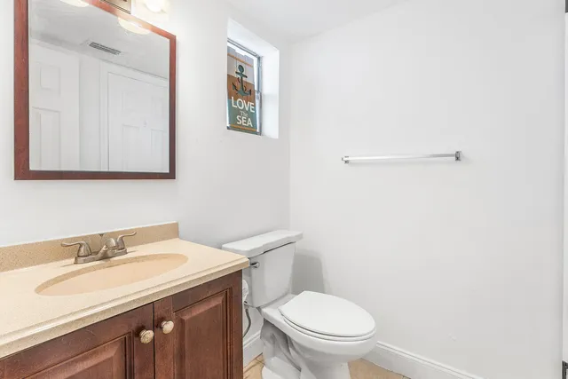 a bathroom with a granite countertop sink and a toilet