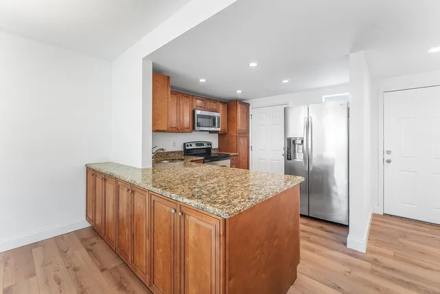 a kitchen with stainless steel appliances granite countertop a refrigerator and a sink