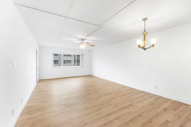 an empty room with windows and ceiling fan