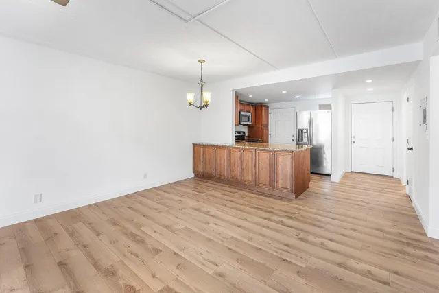 a view of a room with wooden floor and kitchen view