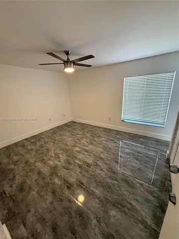 an empty room with a ceiling fan and a window