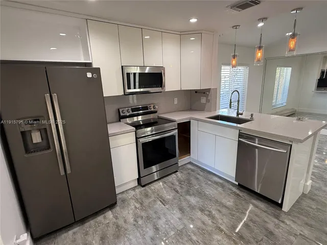a kitchen with stainless steel appliances granite countertop a stove a sink and a refrigerator