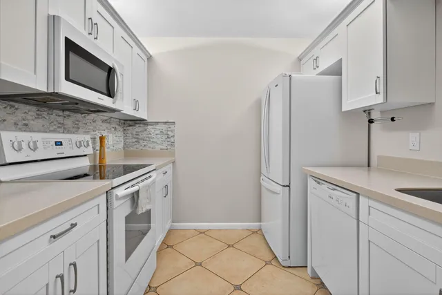 a kitchen with stainless steel appliances granite countertop white cabinets a refrigerator and a stove top oven
