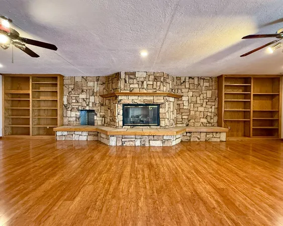 an empty room with wooden floor and fireplace