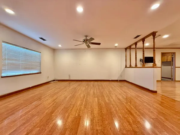 a view of empty room with wooden floor and fan