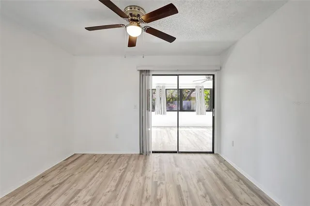 an empty room with wooden floor ceiling fan and windows
