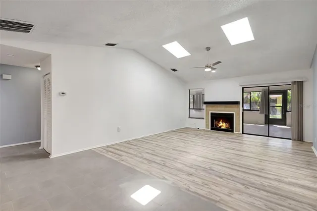 an empty room with wooden floor fireplace and windows
