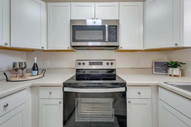 a kitchen with stainless steel appliances granite countertop white cabinets a stove a sink and dishwasher
