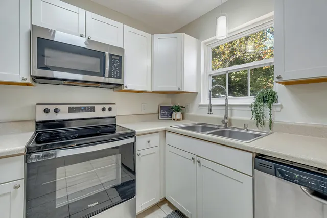 a kitchen with cabinets stainless steel appliances a sink and a window