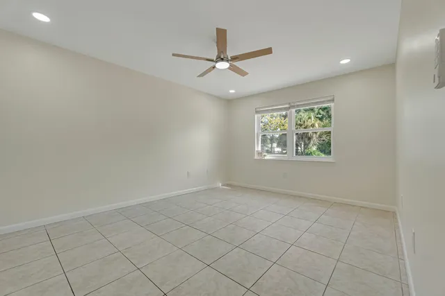 an empty room with ceiling fan and windows