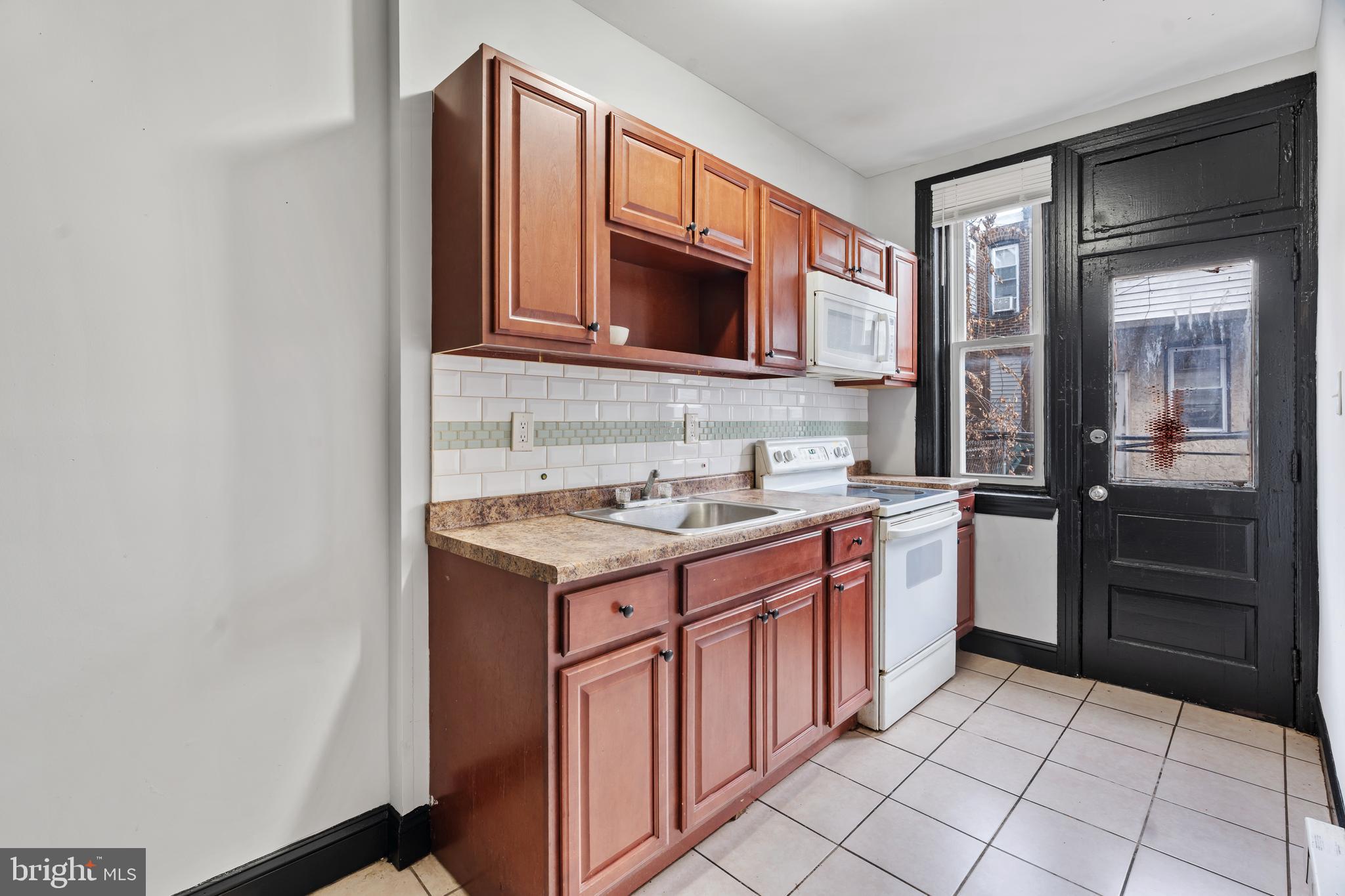 3239 North 26th Street Philadelphia, PA 19129 - Photo 10 of 28 a kitchen with stainless steel appliances granite countertop a stove microwave and a sink