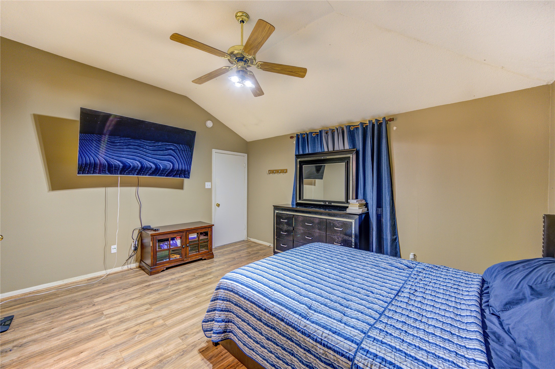 23618 Tree House Lane Spring, TX 77373 - Photo 31 of 46 a bedroom with a bed a dresser and a wooden floor