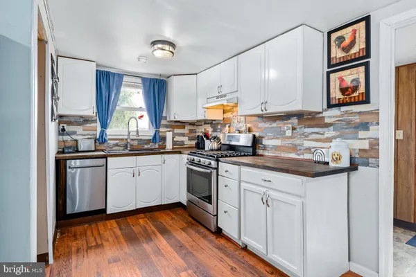 a kitchen with granite countertop a sink cabinets stainless steel appliances and a window