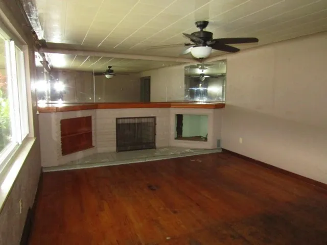 a view of an empty room with a fireplace and wooden floor