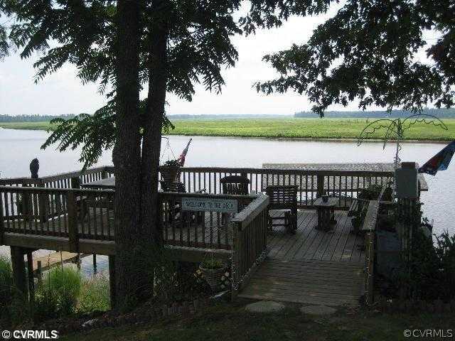 4983 Wakema Road West Point, VA 23181 - Photo 10 of 12 a view of a roof deck with table and chairs couches with wooden floor and fence