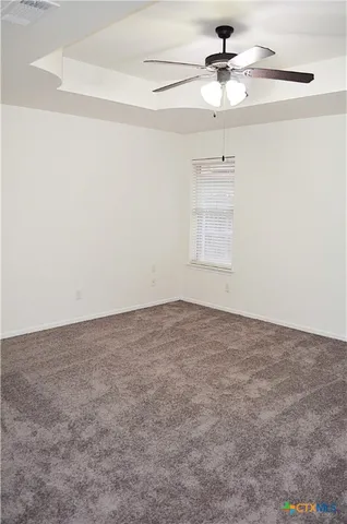 an empty room with a chandelier fan and windows