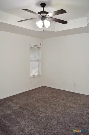 an empty room with a window and a ceiling fan