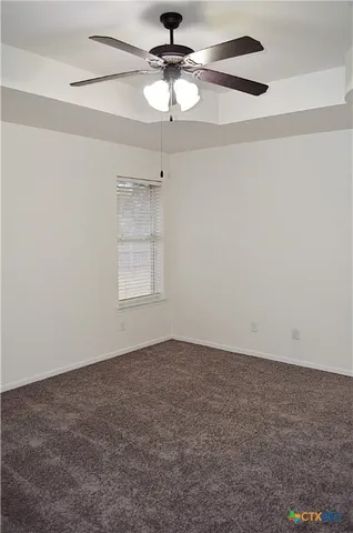 an empty room with a window and a ceiling fan