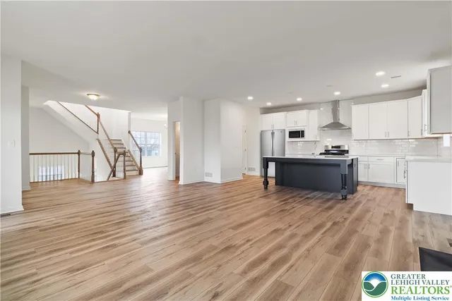 a view of kitchen with kitchen island wooden floors and stainless steel appliances