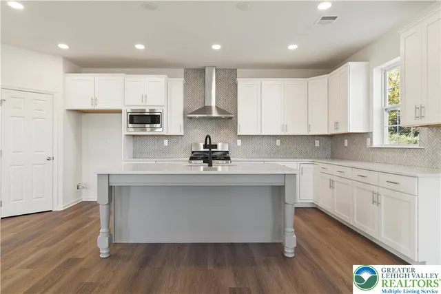 a kitchen with stainless steel appliances granite countertop a white cabinets and wooden floor