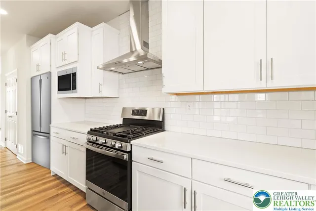 a kitchen with stainless steel appliances a white stove top oven and cabinets