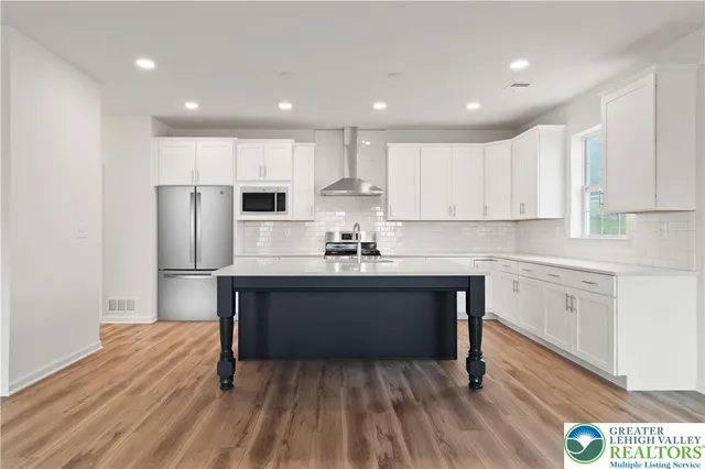 a kitchen with stainless steel appliances granite countertop a white cabinets and wooden floor