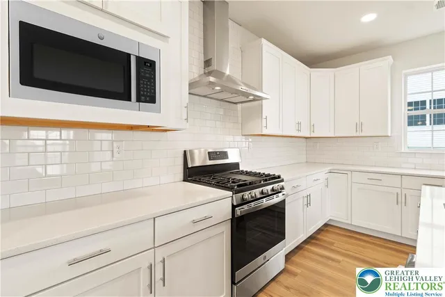 a kitchen with stainless steel appliances white cabinets and a stove top oven