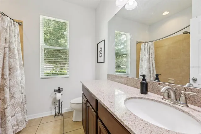 a bathroom with a granite countertop sink a toilet and a mirror