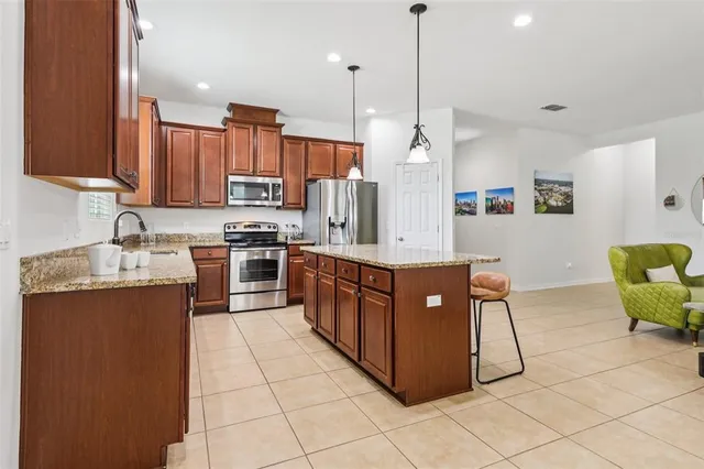 a kitchen with stainless steel appliances granite countertop a sink counter space cabinets and a view of living room
