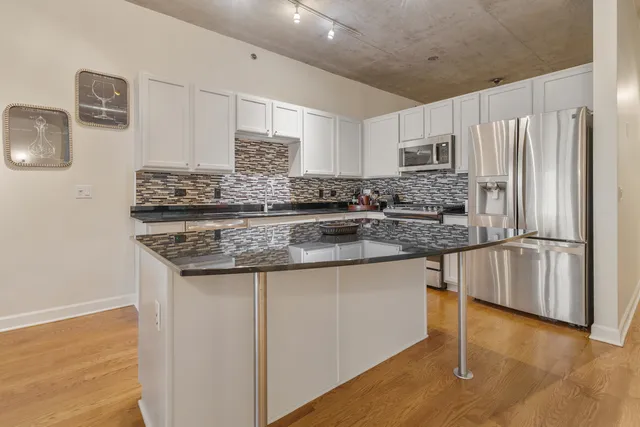 a kitchen with stainless steel appliances granite countertop a refrigerator and a stove top oven