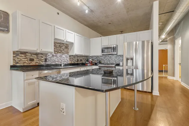 a kitchen with stainless steel appliances granite countertop a sink a stove and a refrigerator