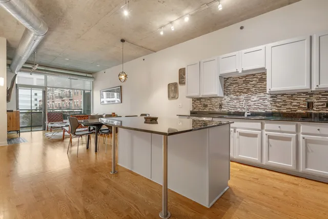 a kitchen with granite countertop a stove a sink a dining table and chairs