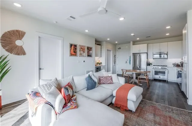 a living room with furniture kitchen view and a wooden floor