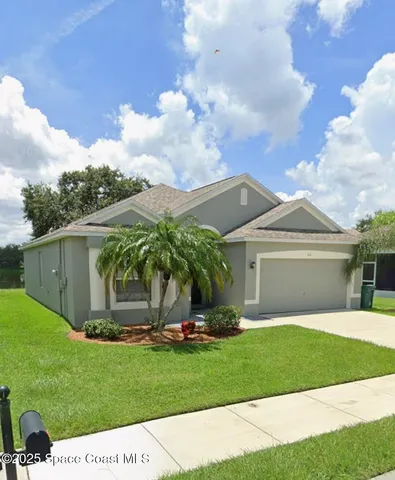 a view of a white house with a big yard and potted plants