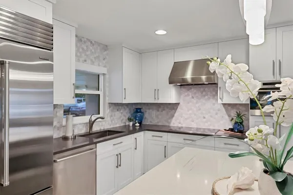 a kitchen with white cabinets and sink
